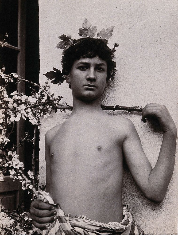 A Sicilian boy, naked from the waist up, his hand level with his shoulder, crowned with leaves. Photograph by W. von…