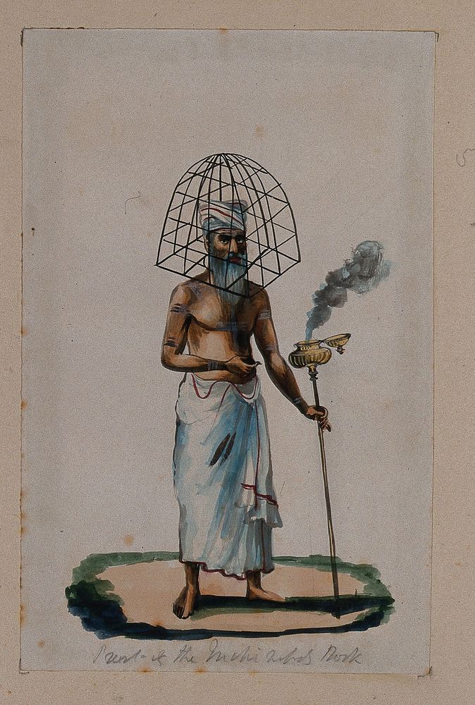 A priest with a protective cage  covering his head, holding a stick with smoke coming out of a pot attached at the top.…