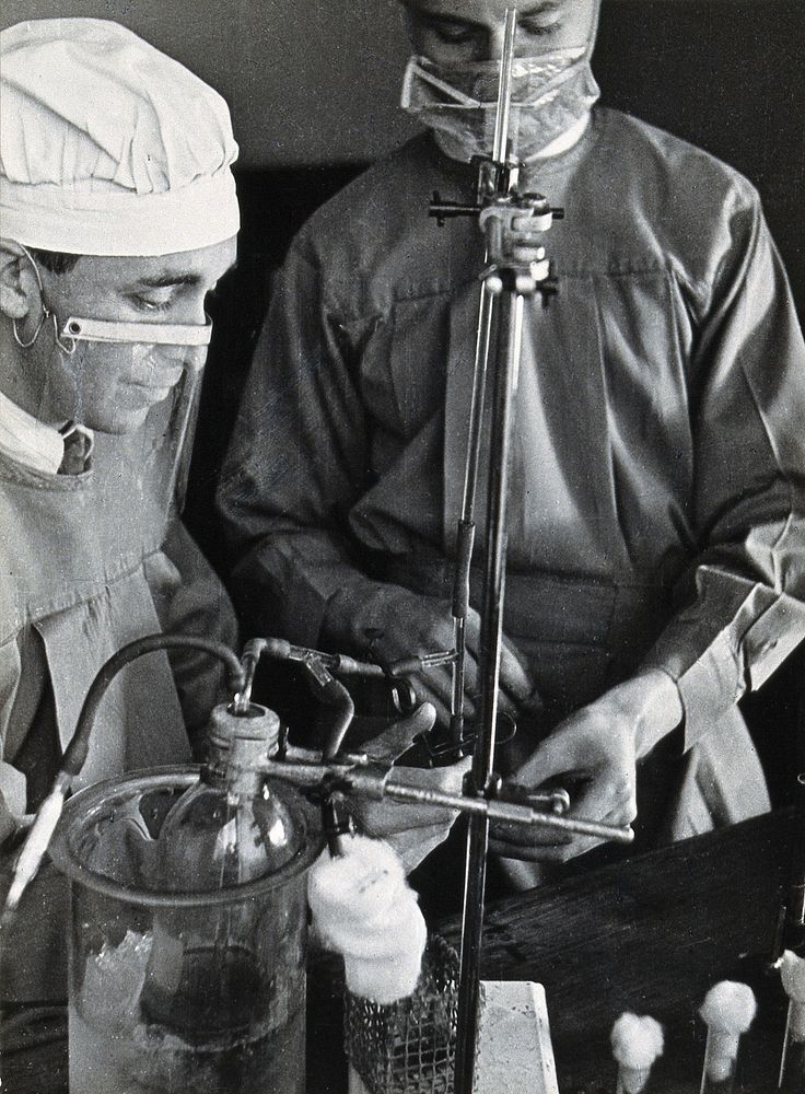 Yellow fever: two scientists wearing face masks at work in a laboratory. Photograph, 1910/1930 .