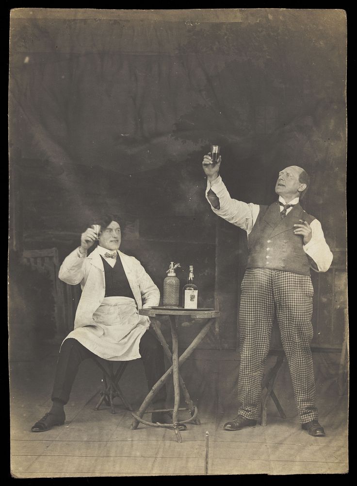 Two sailors pose on stage, holding up a drink. Photographic postcard, 191-.