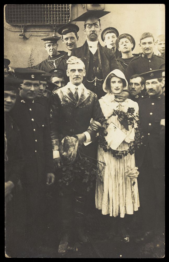 Sailors on H.M.S Dominion, one in bridal drag, conduct a mock wedding on Christmas Day. Photographic postcard, 1915.