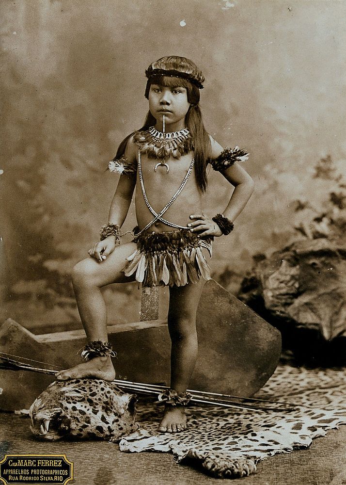 A child of an Amazonian Indian tribe, standing on a leopard skin, in a photographic studio.