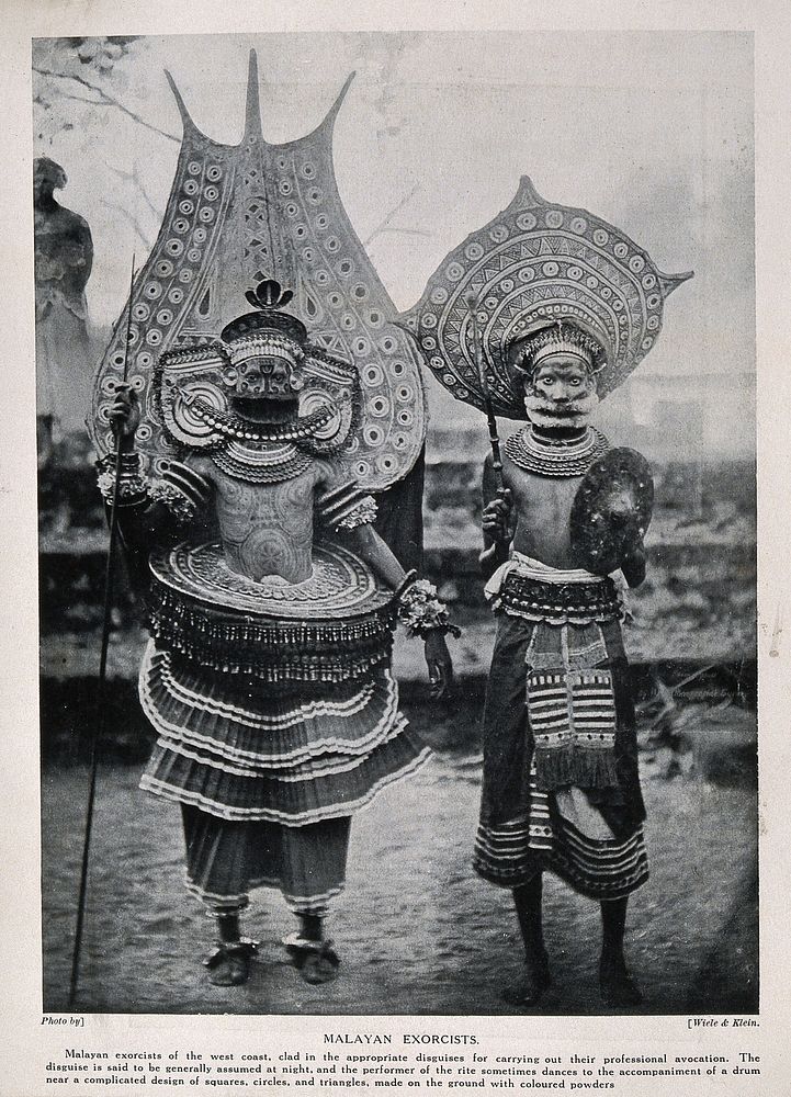 Two Malayan exorcists dressed in elaborate ritual costume. Halftone after a photograph by Wiele & Klein.