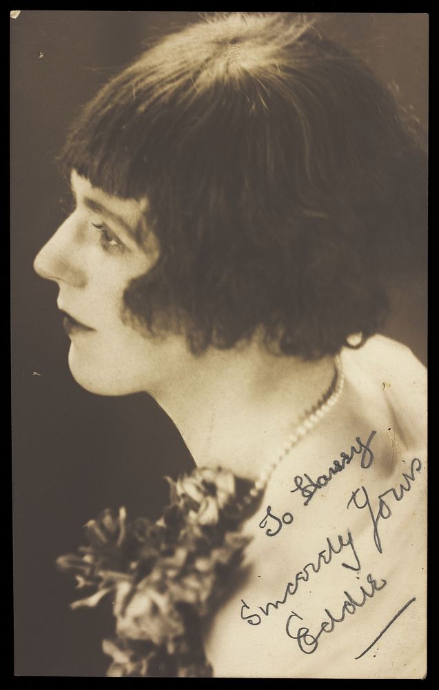 Eddie, a man in drag poses for a close-up, wearing a pearl necklace and styled hair. Photographic postcard, ca. 1925.