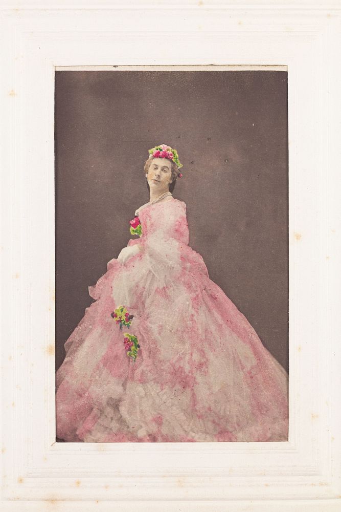 Francis Cowley Burnand, in drag, poses wearing a large pink dress with flowers in his hair. Photograph, ca. 1855.