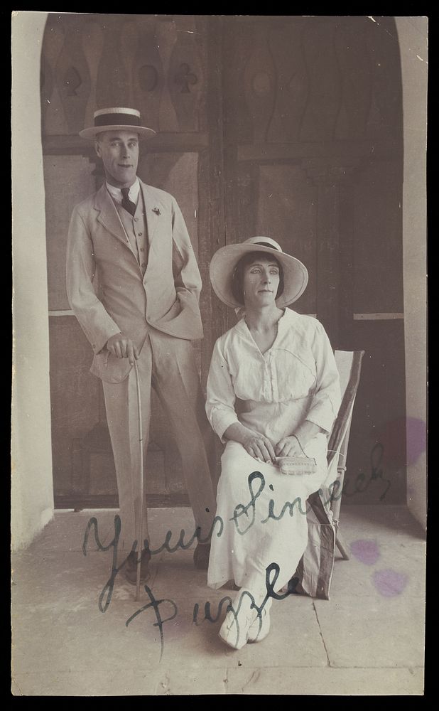 Two men, one in drag, posing in front of a doorway. Photograph, 191-.