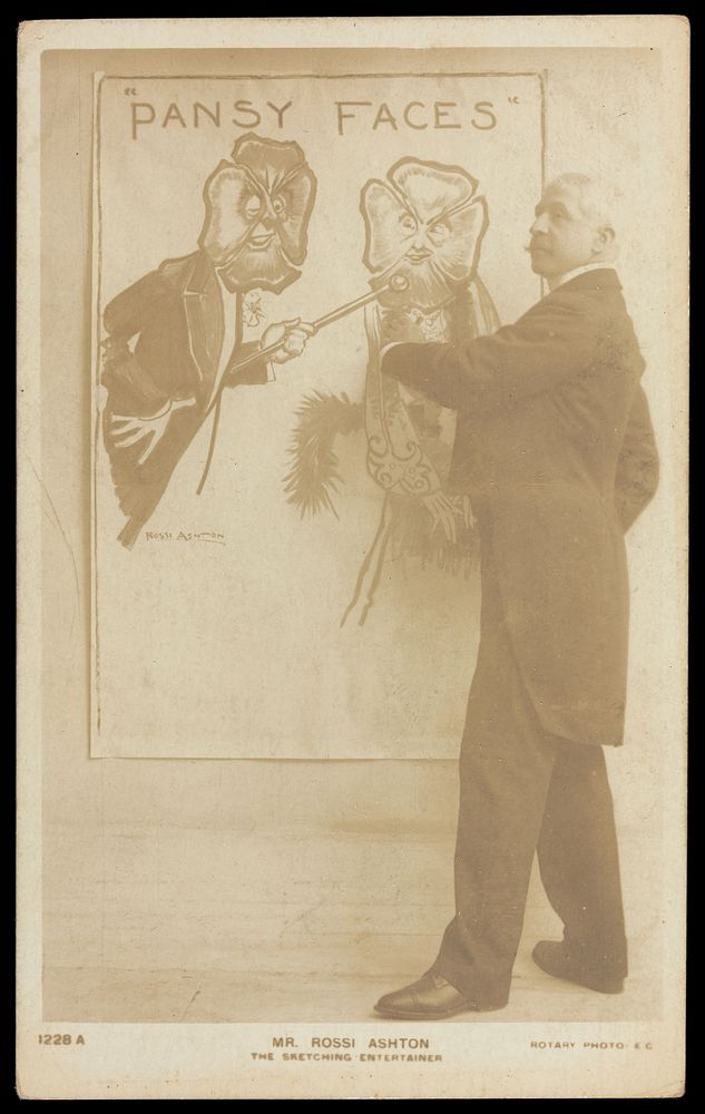 George Rossi Ashton drawing a man and a woman with pansies as faces. Photographic postcard, 190-.