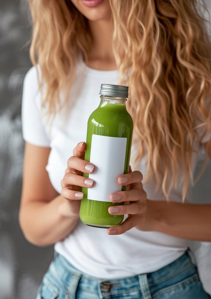 Woman holding a bottle of green detox juice refreshment container drinkware.