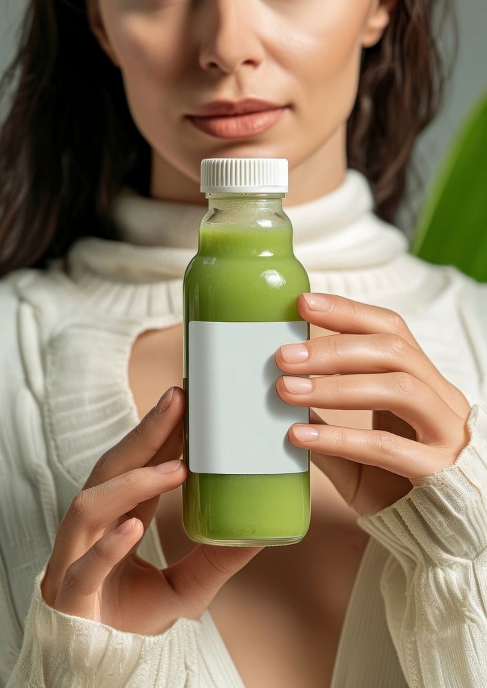 Woman holding a bottle of green detox juice drink refreshment container.