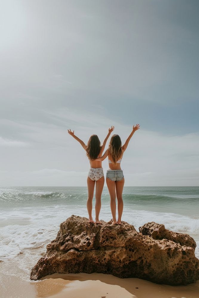 Couple standing on a rock at the beach swimwear outdoors vacation.