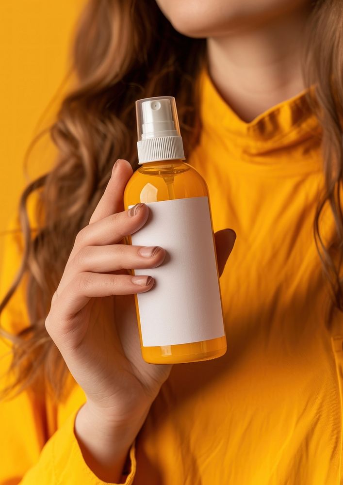 Woman holding a bottle of sunscreen spray cosmetics perfume container.