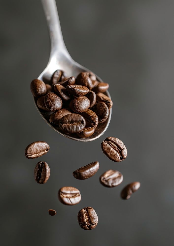 A coffee beans falling on the spoon refreshment ingredient freshness.