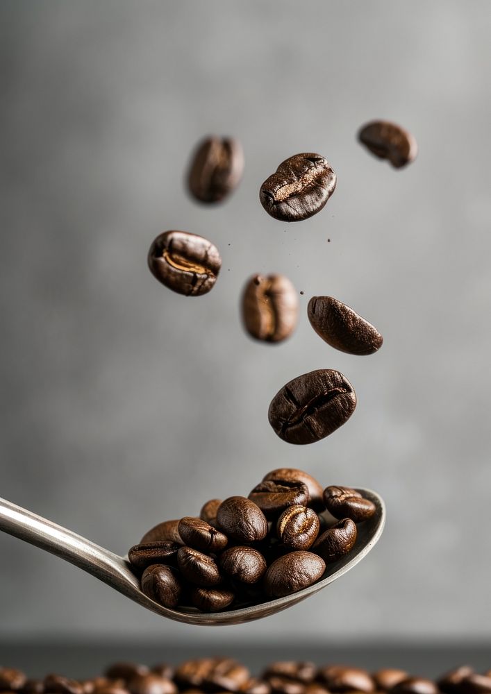 A coffee beans falling on the spoon invertebrate refreshment ingredient.
