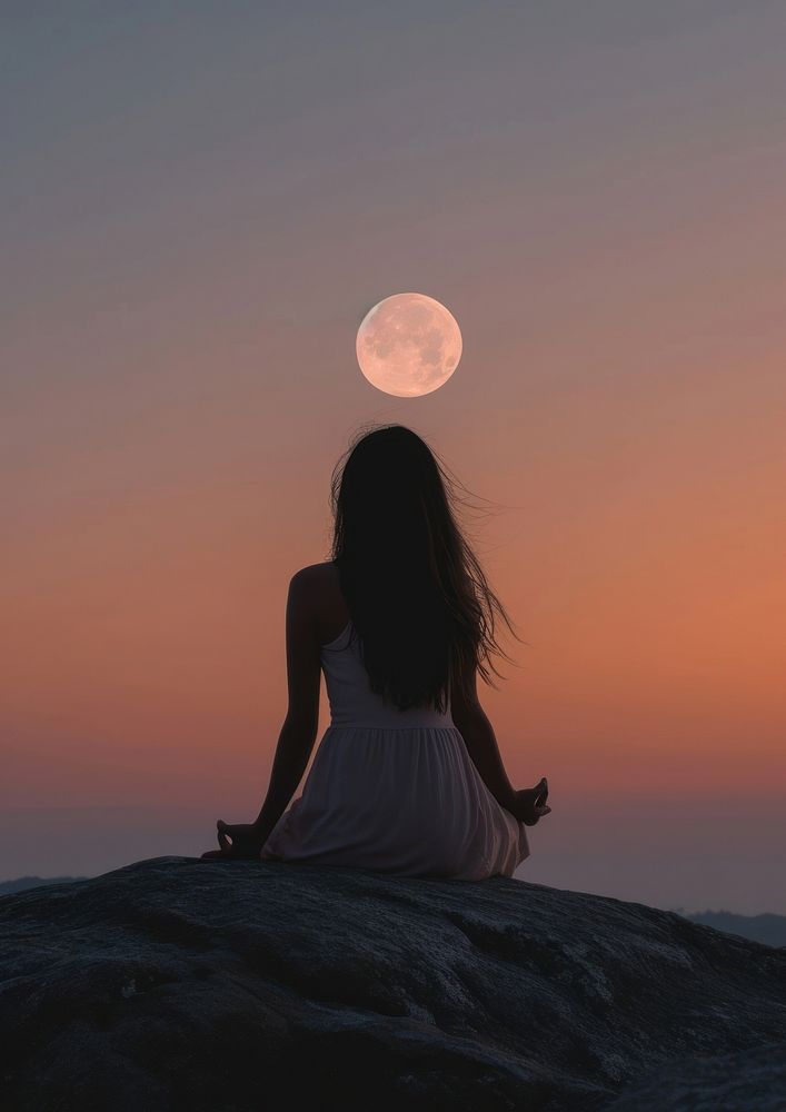 A woman silhouette sitting put the hand together or doing yoga on the mountain in front of the moon astronomy outdoors…