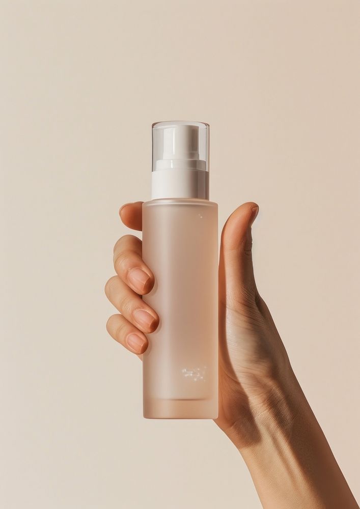 Hand holding skincare bottle cosmetics perfume container.