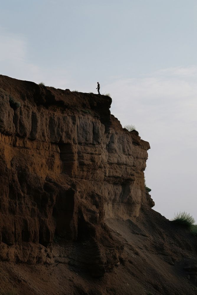 Photo of a man hiking cliff landscape outdoors.