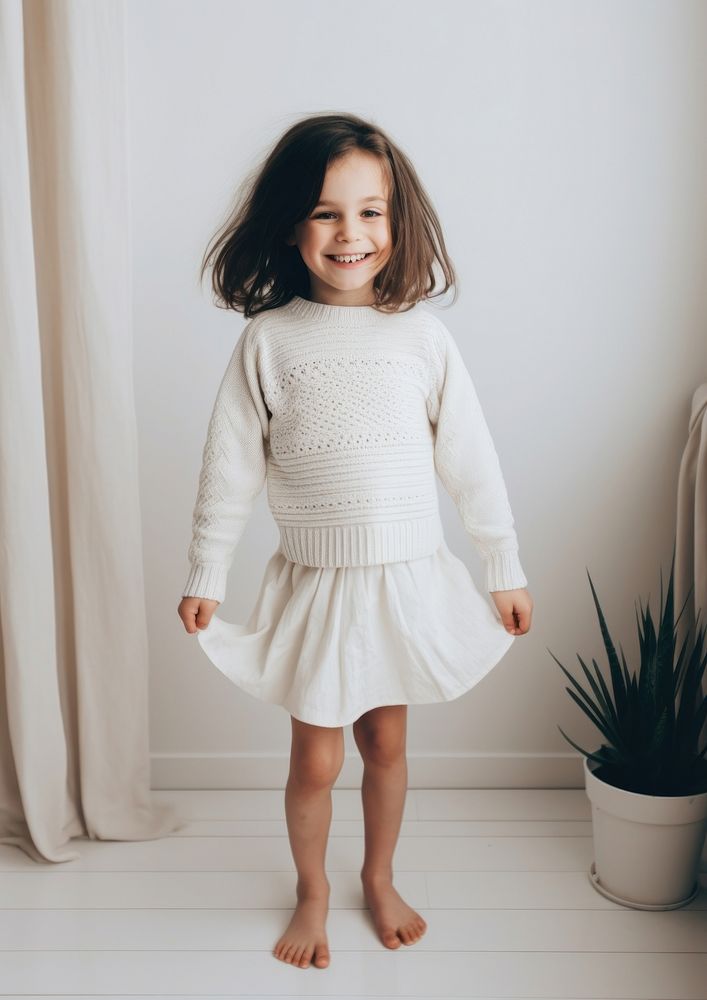 Cheerful kid wearing white knit skirt sweater sleeve dress.