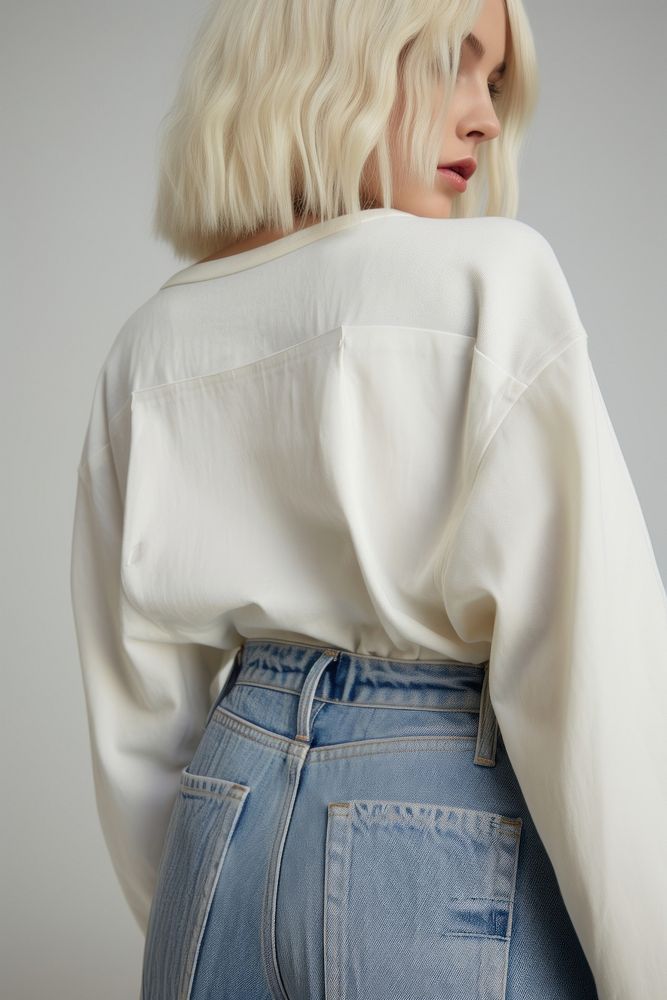 Super close up woman wearing bottom denim faded jeans with empty embroider label on back side fashion blouse sleeve.
