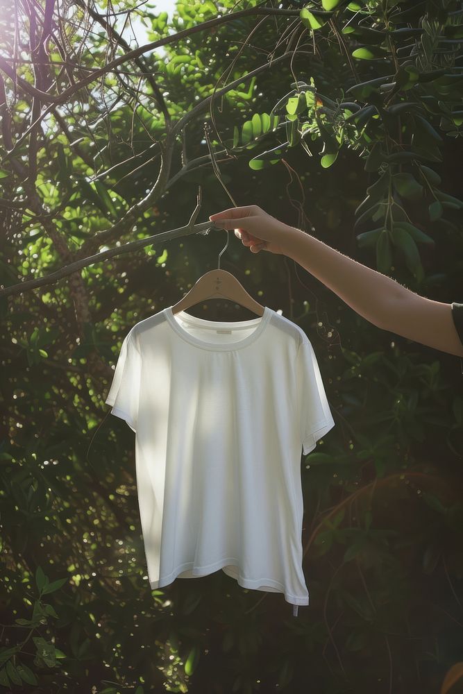Hand holding hanger with white t shirt outdoors t-shirt nature.
