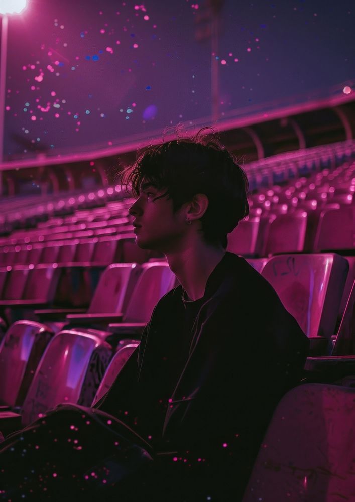 Young man sitting on seats at empty stadium portrait purple photo.