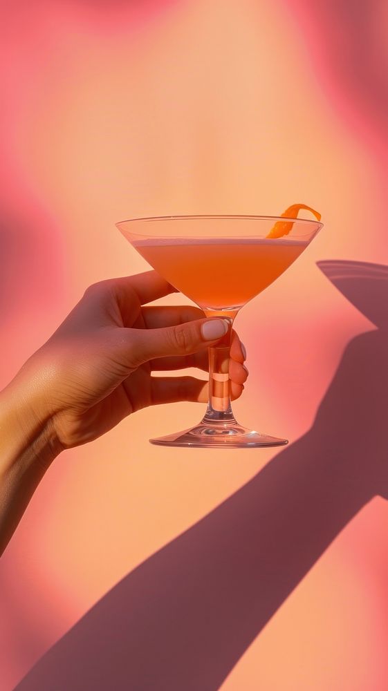 Hand holding cocktail glass martini drink red.