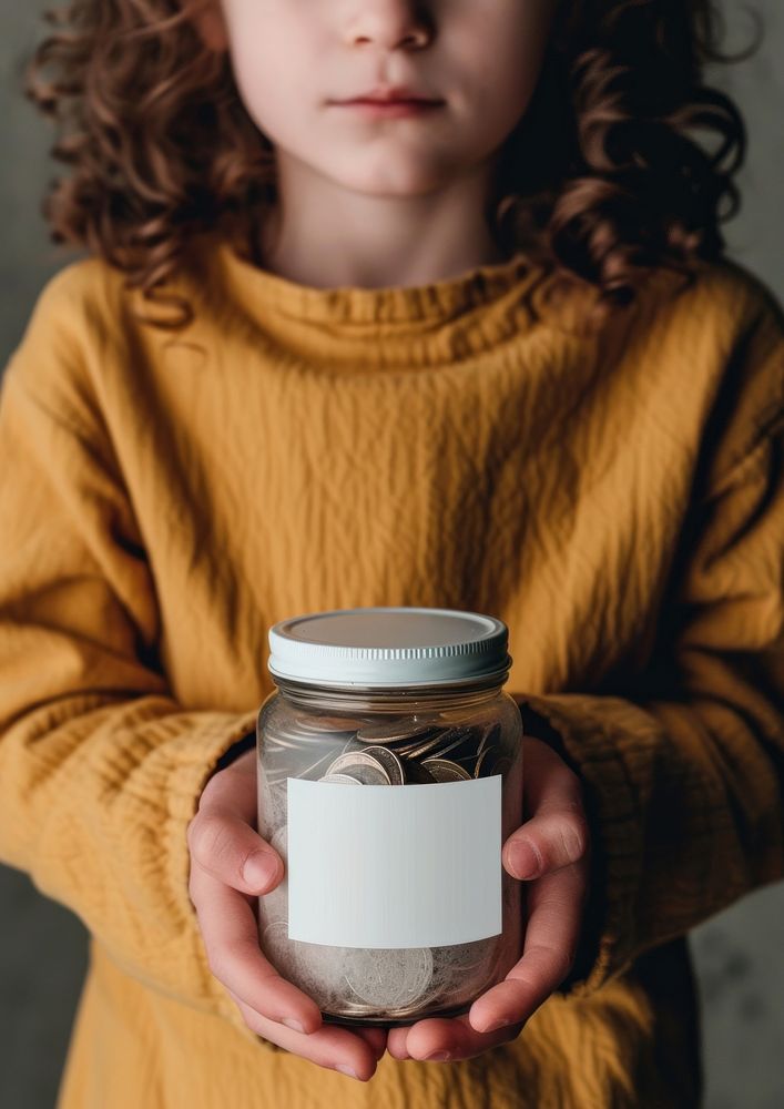 Kid holding a jar of coins container portrait standing.