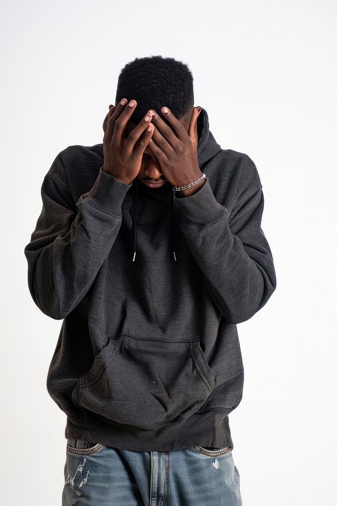 Depressed young black man hiding head in hands sweatshirt white background disappointment.