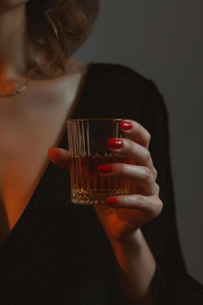 Woman hand with red nail hold a glass of whisky drinking refreshment cosmetics.