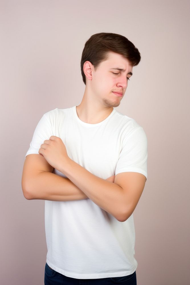 Young man having shoulder pain clothing apparel t-shirt.