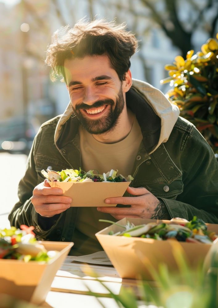 A photo of happy man eating photography outdoors laughing.