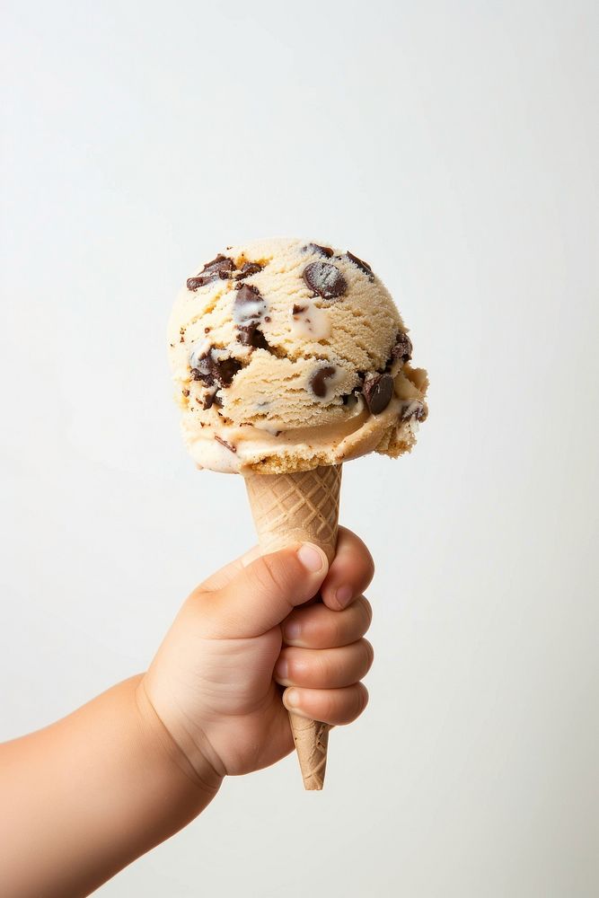 Hand holds a melting chocolate chip cookie ice cream dessert creme food.