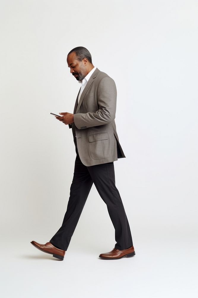 Man looking at his mobile phone walking business photo.