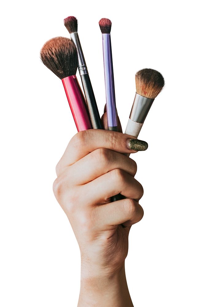 Hand holding makeup brushes, showcasing various brush types. Makeup brushes for beauty routines. Diverse makeup tools for…