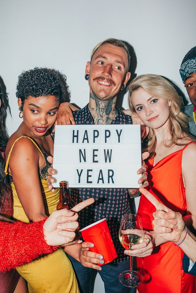 Group celebrating New Year with diverse friends. Happy New Year sign held by friends. Diverse group, New Year joy, friends…