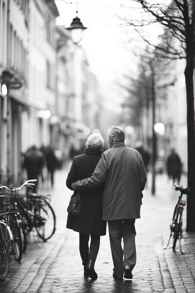 Elderly couple walking arm-in-arm bicycles street urban.