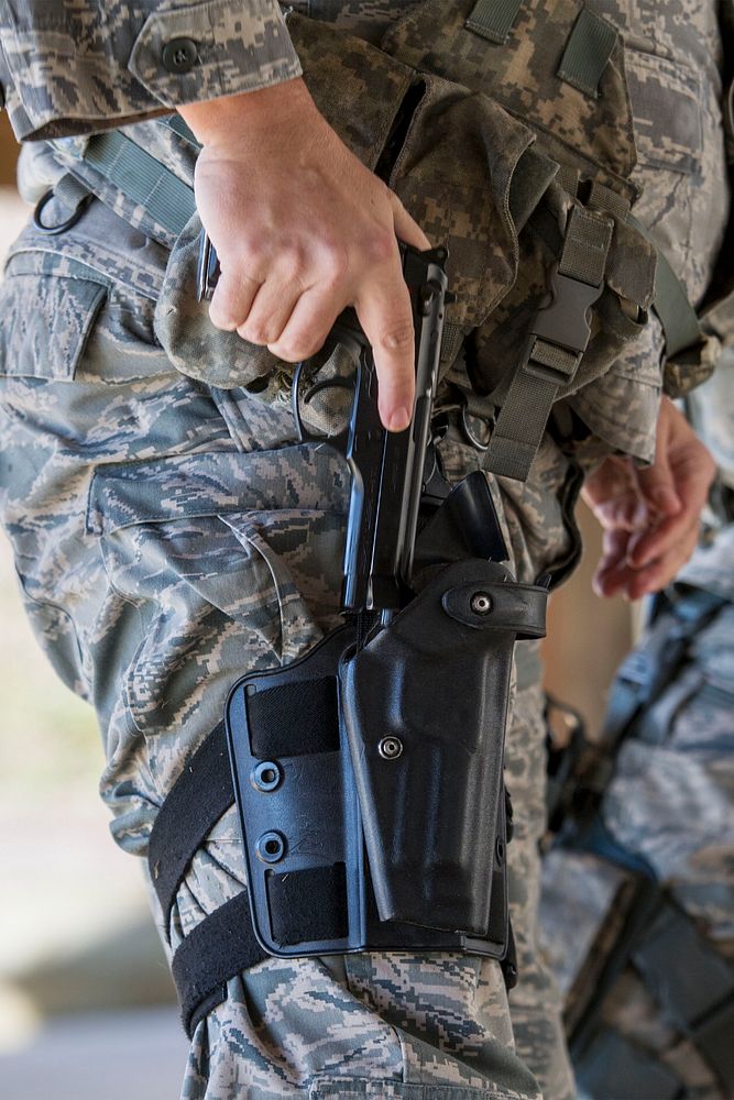 U.S. Air Force Staff Sgt. Michael Lepp, assigned to the 169th Security Forces Squadron, holsters his M9 Beretta pistol…