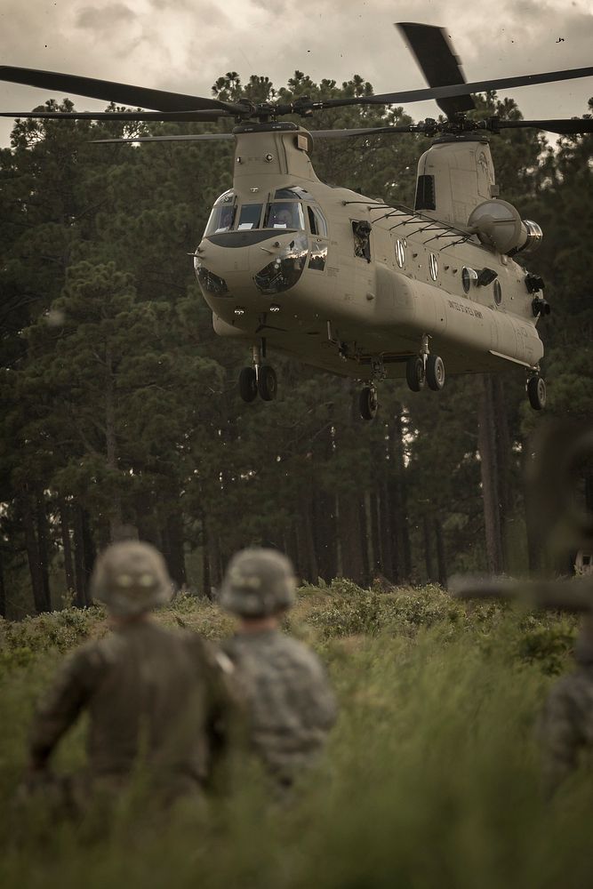 Two U.S. Soldiers assigned to the 82nd Airborne Division Artillery, watch as a CH-47 Chinook with the 82nd Combat Aviation…