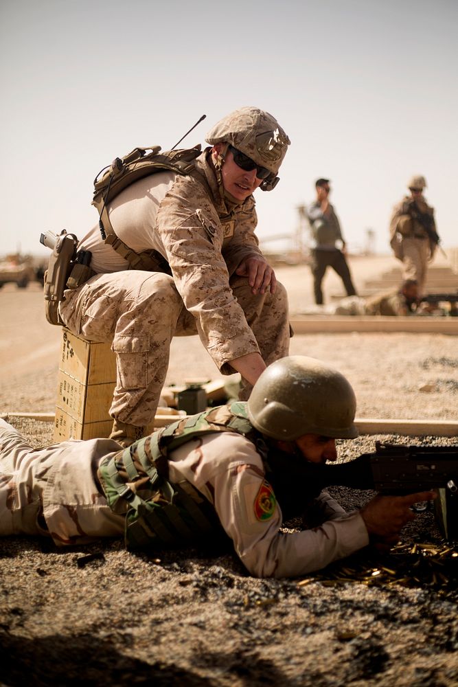 A U.S. Marine Corps adviser assigned to Task Force-Southwest coaches a soldier with the Afghan National Army during a M240B…