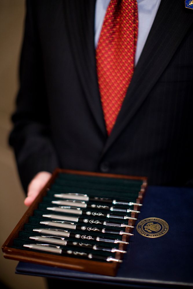 Deputy Staff Secretary Peter Rundlet holds a tray of pens for President Barack Obama as he signs a memorandum for closer…