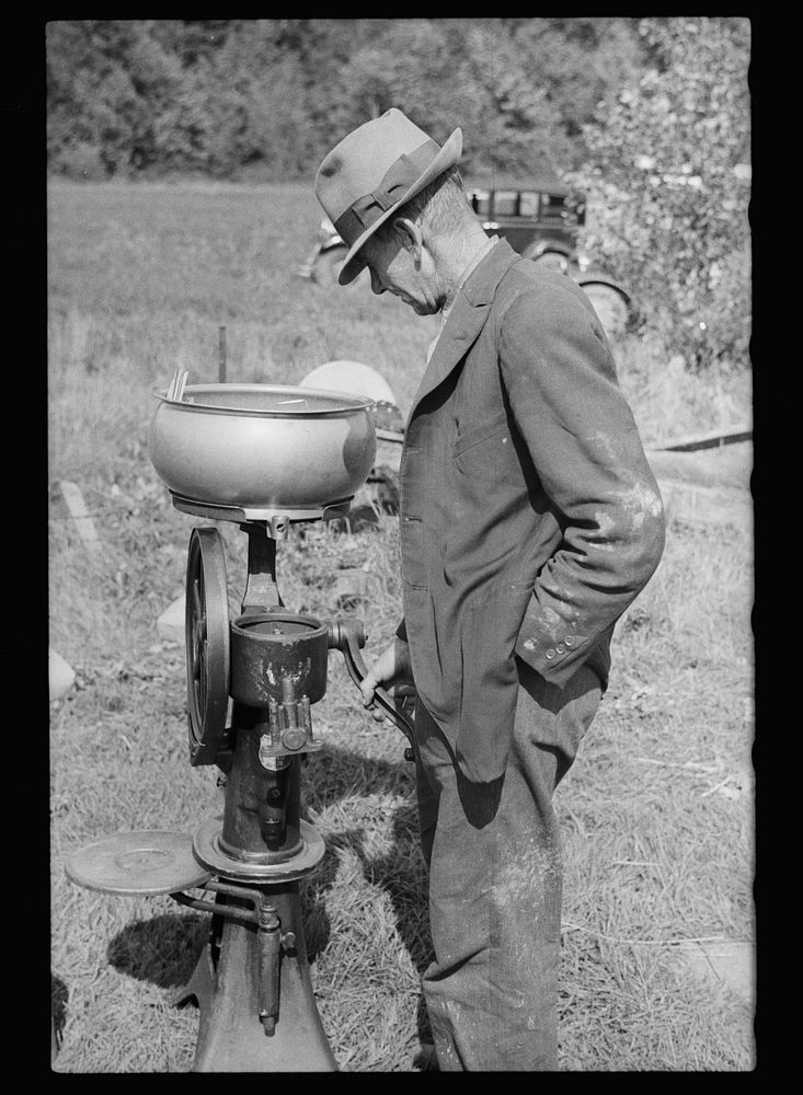 [Untitled photo, possibly related to: Farmer examining cream separator. Auction near Tenstrike, Minnesota]. Sourced from the…