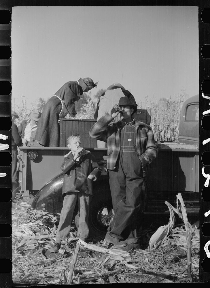 Farmer and son at refreshment stand, mechanical corn picker contest, Hardin County, Iowa. Sourced from the Library of…