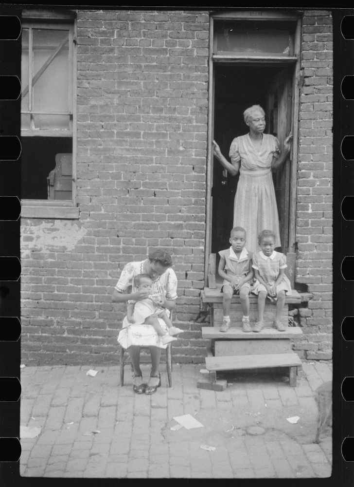 [Untitled photo, possibly related to:  family in front of their alley dwelling. The older woman is a cleaning woman in the…