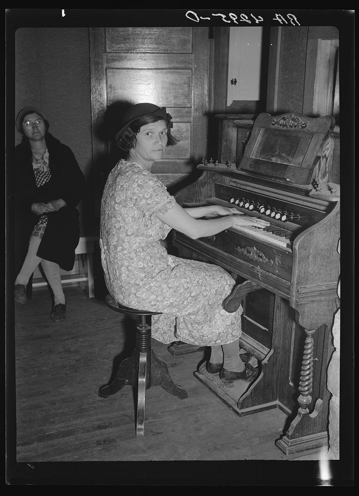 Wife of a resettled farmer playing organ at meeting of the Falls City Farmsteads Cooperative, Nebraska. Sourced from the…