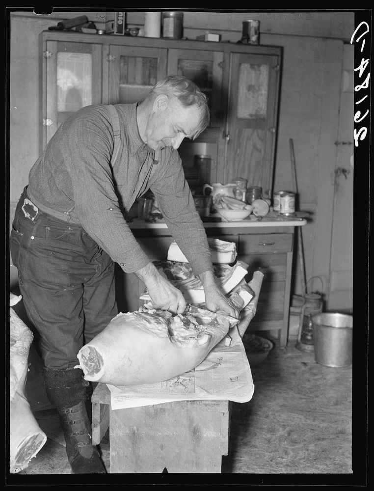 Frank Walker, farmer cutting meat in his farm home near Dalton, New York. Sourced from the Library of Congress.