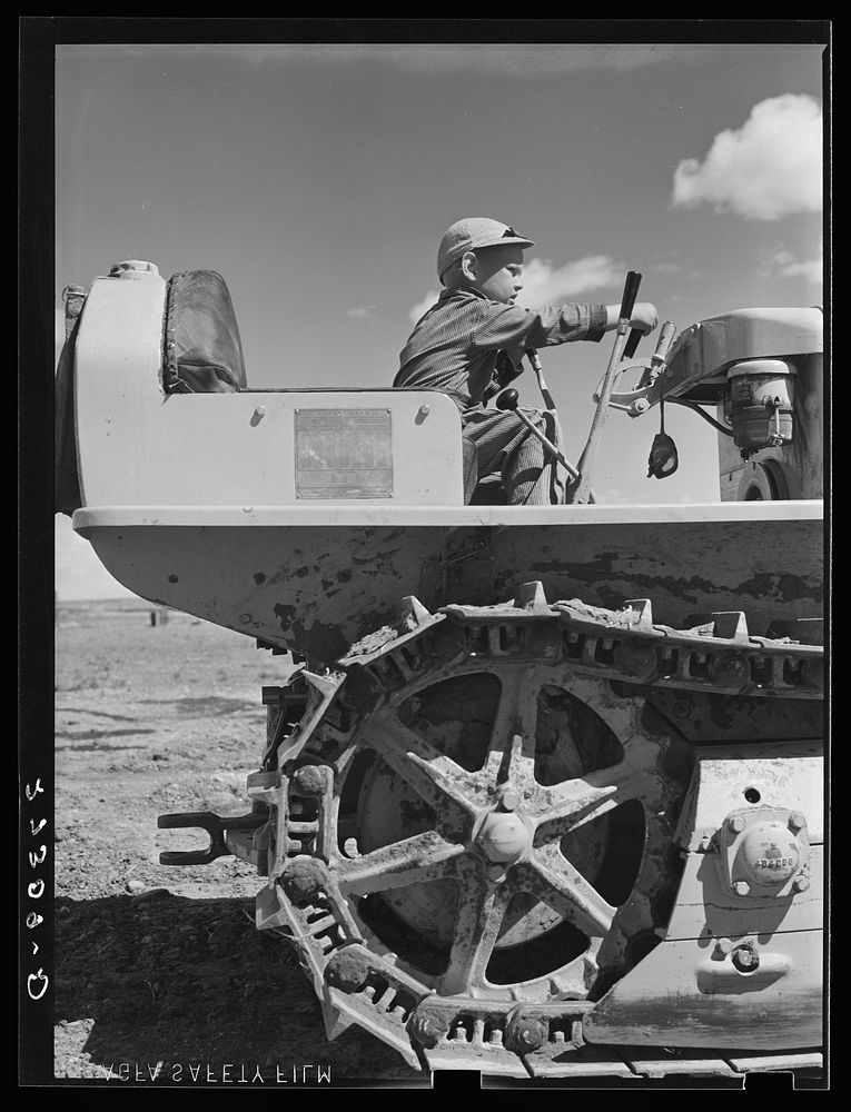 Wheat farmer's son playing with tractor. Cascade County, Montana. Sourced from the Library of Congress.