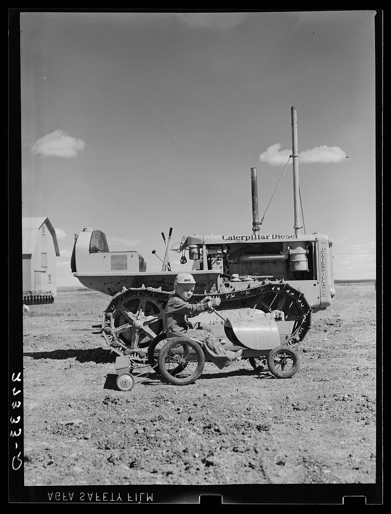 Johnnie Sheffels with his toy tractor and seed drill. Cascade County, Montana. Sourced from the Library of Congress.