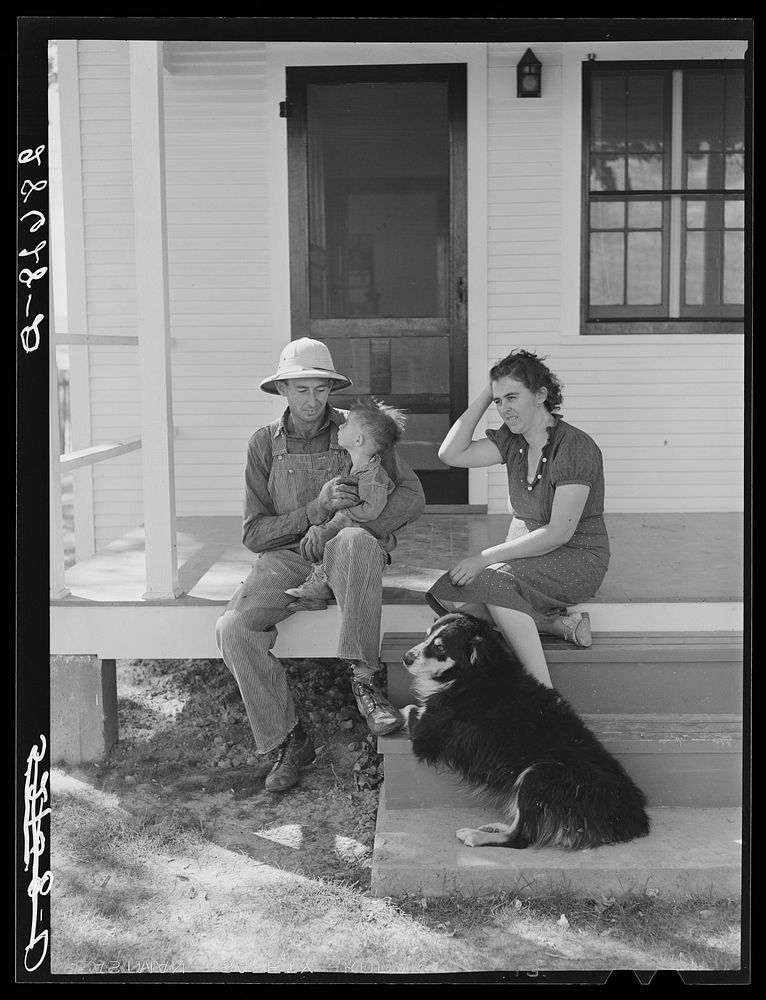 Carl Higgins family, purchase borrowers, on the porch of their home in Mesa County, Colorado. Sourced from the Library of…