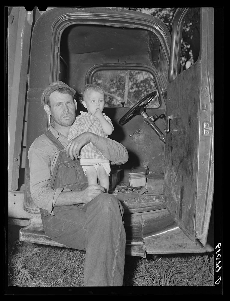 Migrant fruit worker and child camped with fifteen other families along roadside in Berrien County, Michigan. Sourced from…
