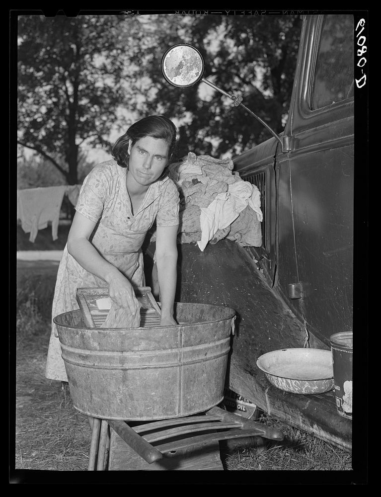 Mother of migrant fruit picking family doing family wash in roadside camp where fifteen farmers are living. Berrien County…