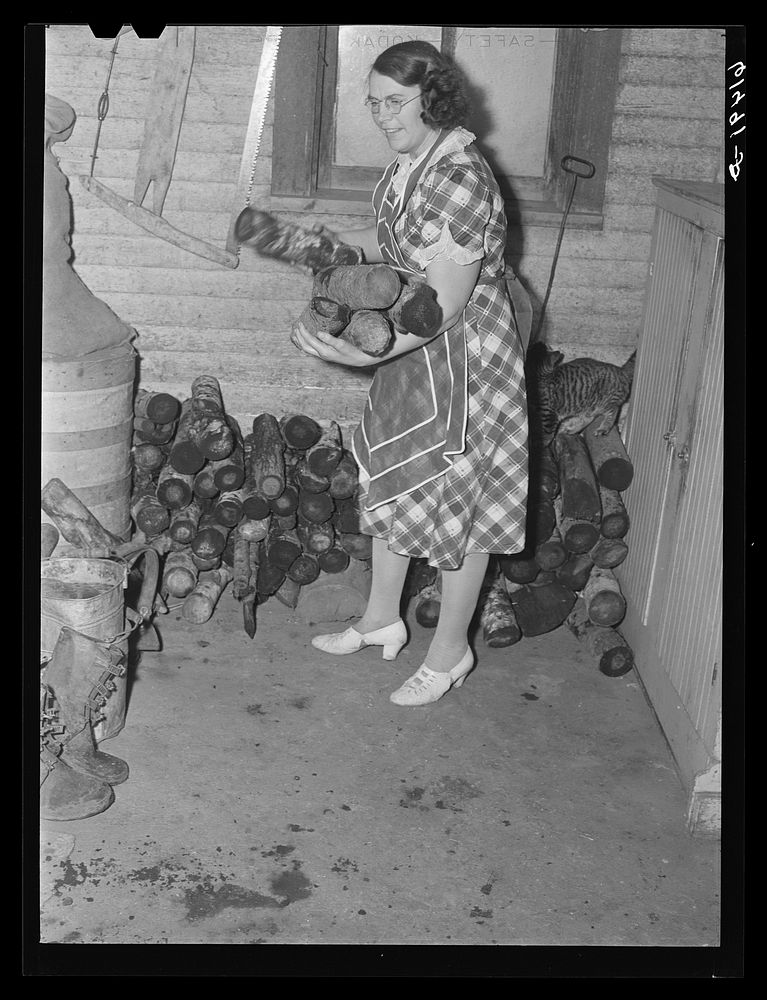 Mrs. Sauer bringing in wood for kitchen stove. Cavalier County, North Dakota. Sourced from the Library of Congress.